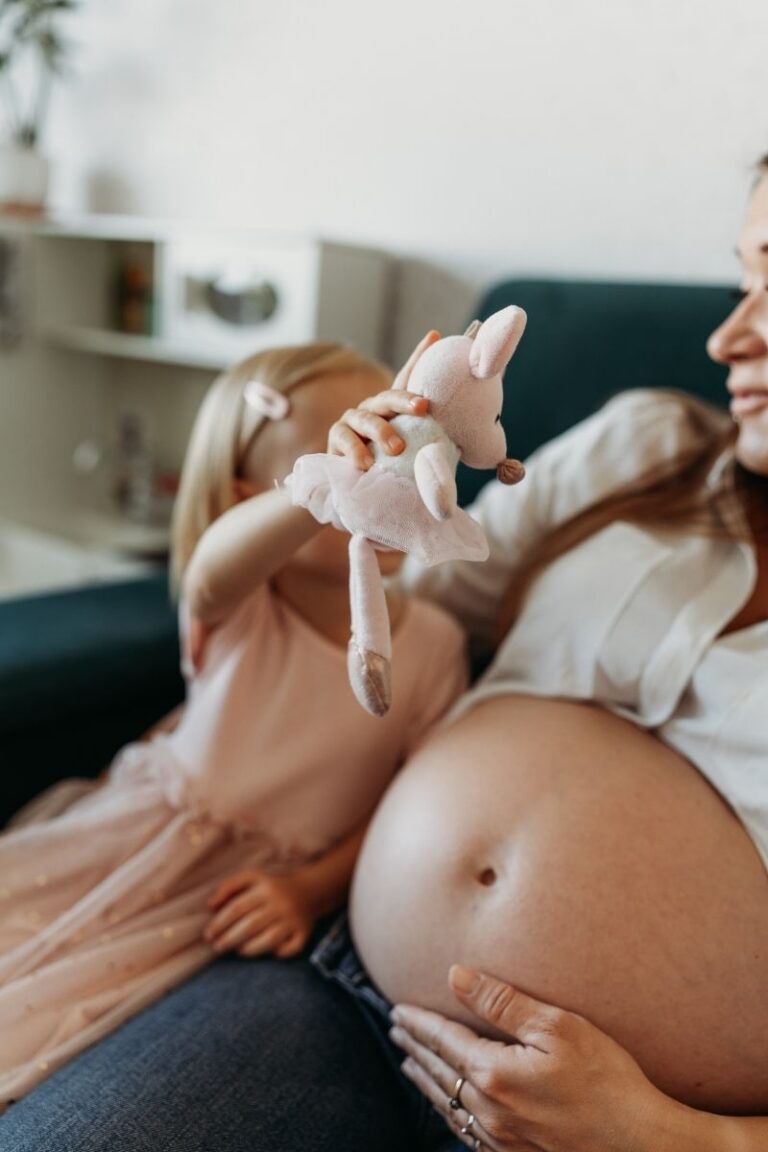 Mama w ciazy bawi sie z coreczka na kanapie podczas domowej sesji ciazowej w Warszawie - Magda Zaborowska Fotografia