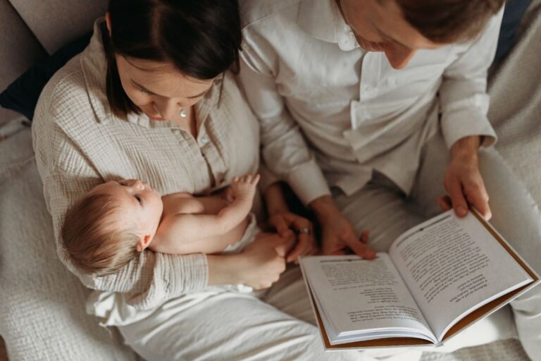 Mama trzyma noworodka a tata czyta ksiazke podczas domowej sesji noworodkowej w Warszawie - Magda Zaborowska Fotografia